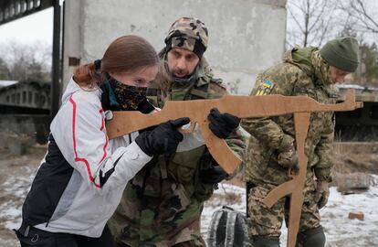 Una mujer aprende a empuñar un arma, con un rifle de cartón, en una sesión de las Fuerzas de Defensa Territorial, en Kiev, el 29 de enero.