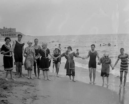 Un grup d'homes i dones a la platja d’Arenys de Mar, cap al 1920.