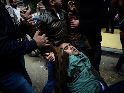 Dos manifestantes opositores evacuan a un herido en El Cairo este s&aacute;bado.