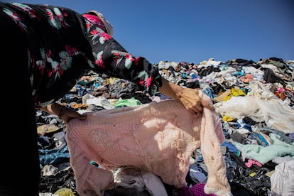 Una mujer busca prendas de ropa en un basurero masivo, en Iquique (Chile), en 2021.