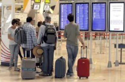 Varios pasajeros consultan paneles informativos en la T4 del aeropuerto de Barajas. EFE/Archivo