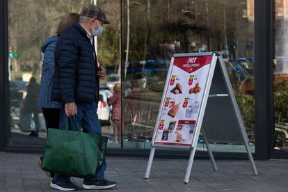 Una pareja mira las ofertas en la entrada de un supermercado en Madrid.