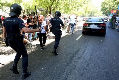 Varios policias protegen un coche VTC durante la manifestacion de taxistas en Madrid.