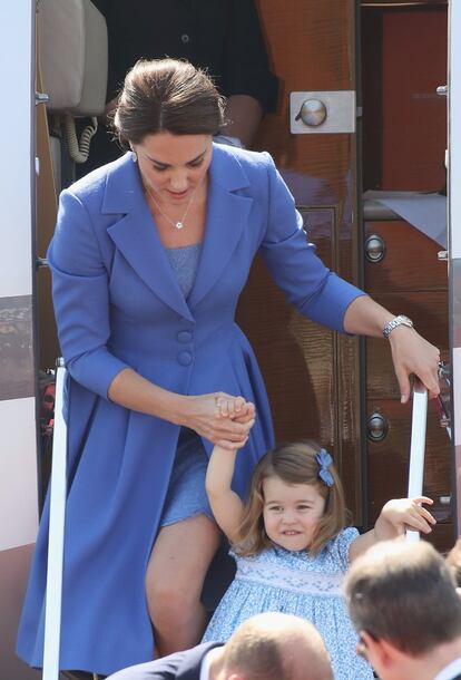 La duquesa de Cambridge, Kate Middleton, ayuda a bajar del avión a su hija, la princesa Carlota, que lleva un vestido azul a juego con su madre. Un tono que se ha leído en algunos medios como un color azul Europa, pues también con esta gira el príncipe y su familia pretenden mejorar la imagen de Reino Unido tras el voto a favor del Brexit.