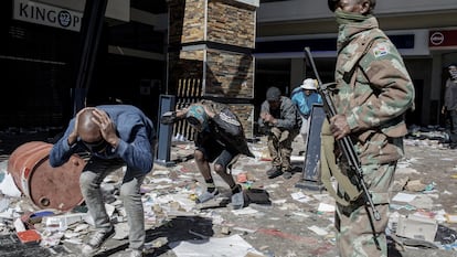 Militar vigia homens detidos por saque em um centro comercial de Soweto no dia 13.