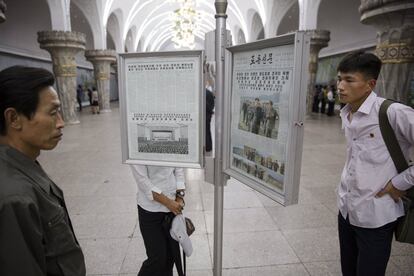 Unos ciudadanos leen los periódicos que se muestran en una estación de metro en Pyonyang.