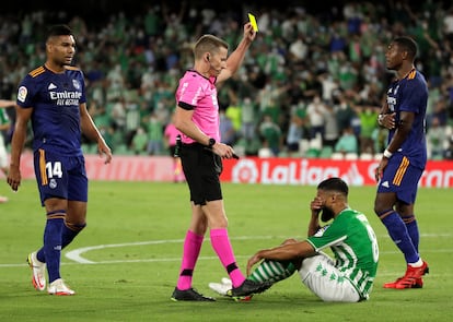 El árbitro Hernández Hernández enseña tarjeta amarilla al bético Nabil Fekir por simular un penalti ante el Madrid.