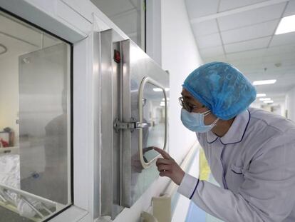 Un médico habla con su compañero en una cabina de aislamiento en un hospital de Wuhan.