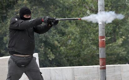 Un manifestante enmascarado dispara un proyector a la policia antidisturbios en Atenas.