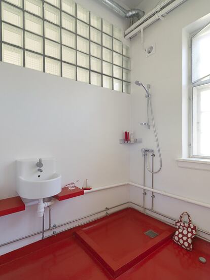 El baño es esencial, con un lavamanos circular de Ikea y con el pavimento y el plato de ducha pintados de color rojo.