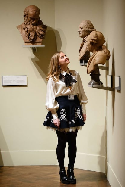 A museum assistant poses with "Bust of a Man" by Augustin Pajou (1761) (L), "Bust of a Man" by Pierre Merard (1786) (C) and "Michel-Jean Sedaine" by Augustin Pajou (1775) displayed within the Victoria and Albert museum's new "1600-1815" galleries in London on December 7, 2015. The V&A's seven new gallery areas hold nearly 1,100 objects and will open to the public on 9 December, 2015. 
AFP PHOTO / LEON NEAL