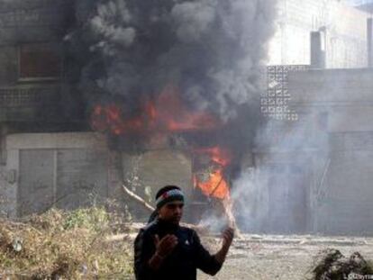 Un hombre junto a una casa en llamas bombardeada por el ejército Sirio en la ciudad de Homs el 12 de febrero.