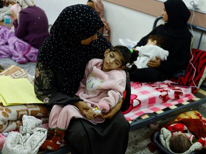 Una madre palestina tiene en brazos a su hija, Israa, que es cuadripléjica y sufre una severa malnutrición, en el centro de salud de al-Awda, en la ciudad de Rafah, en el sur de la franja de Gaza, el 12 de marzo de 2024