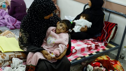 Una madre palestina tiene en brazos a su hija, Israa, que es cuadripléjica y sufre una severa malnutrición, en el centro de salud de al-Awda, en la ciudad de Rafah, en el sur de la franja de Gaza, el 12 de marzo de 2024