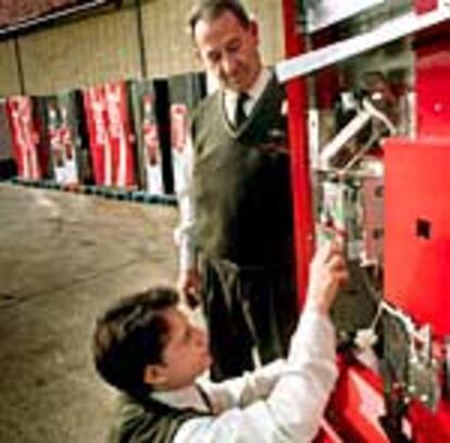 Dos empleados de una empresa de refrescos instalan el monedero electrónico en la máquina de bebidas.