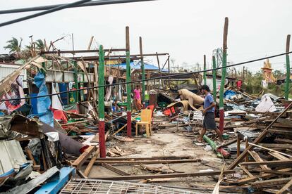 Local residents walk past damaged buildings after Cyclone Mocha in Sittwe township