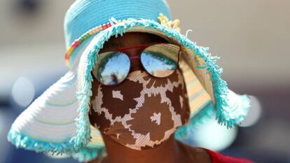 Una mujer con mascarilla acude a por comida que están repartiendo las autoridades en Sudáfrica.