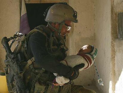 Un soldado holandés sostiene a un bebé durante una misión ayer en Baluchi, Afganistán.