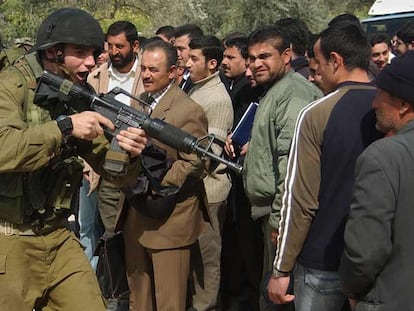 Un soldado israelí apunta con su arma a varios palestinos que esperan para cruzar un puesto de control ayer cerca de Nablus (Cisjordania).
