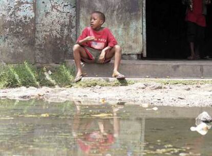 Un niño se sienta junto a un charco de aguas fecales en un distrito de Harare, la capital de Zimbabue