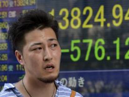 Un viandante pasa por delante de una pantalla que muestra la cifra alcanzada por el índice Nikkei de la Bolsa de Tokio. EFE/Archivo