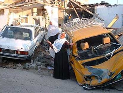 Unas mujeres lloran delante de los coches y viviendas que fueron alcanzados por el fuego israelí en el campo de refugiados de Rafá, en Gaza.