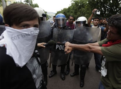 Un partidario del depuesto presidente Zelaya simula estar esposado delante de policías antidisturbios en Tegucigalpa.