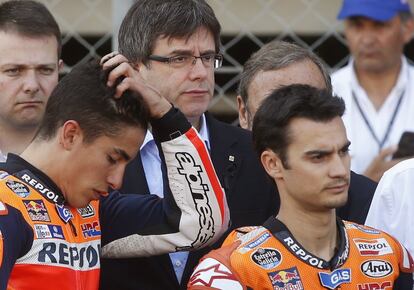 Los pilotos Dani Pedrosa (d) y su compañero de equipo Marc Márquez (i), junto al presidente de la Generalitat de Catalunya, Carles Puigdemont (c), durante el minuto de silencio en memoria del piloto español de Moto2 Luis Salom, fallecido tras el accidente en los entrenamientos del Gran Premio de Catalunya de motociclismo que se celebra en el Circuito de Catalunya en Montmeló (Barcelona). 