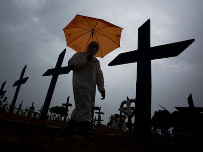 Homem com roupa de proteção passa diante das tumbas com vítimas da covid-19 no cemitério de Nossa Senhora Aparecida, em Manaus (AM), em 25 de fevereiro.