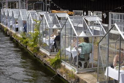Clientes de un restaurante de Ámsterdam comen sentados en pequeñas instalaciones transparentes utilizadas para cumplir con las restricciones impuestas por el Gobierno holandés para frenar el avance del coronavirus.