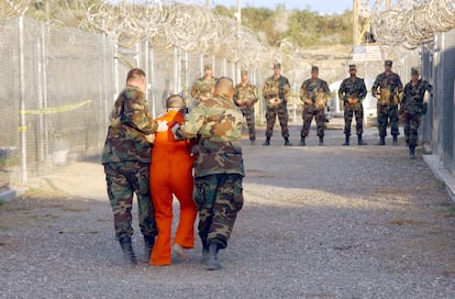 Dos militares trasladan a un detenido, vestido con un mono naranja, a su celda, en enero de 2002 en la cárcel de Guantánamo.