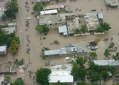 Varios vecinos de la ciudad de Gonaives caminan por las calles anegadas de la localidad haitiana.