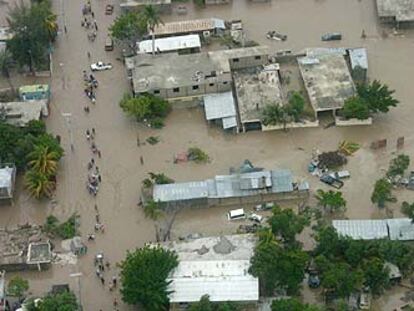 Varios vecinos de la ciudad de Gonaives caminan por las calles anegadas de la localidad haitiana.