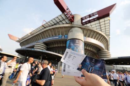 Un simpatizante del partido muestra dos entradas fuera del estadio.