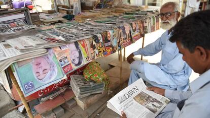 Un hombre lee un ejemplar del periódico 'Dawn' en un kiosko. 