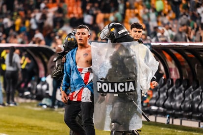 Un hincha del Atlético Junior es escoltado por la Policía en el terreno de juego durante los enfrentamientos en el estadio Atanasio Girardot, en Medellín, el 26 de septiembre de 2024.