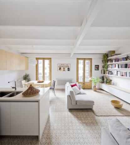 En esta vivienda de Barcelona, diseño de A&EB, se utilizan los muebles altos de la cocina como espacio de almacenaje del salón.