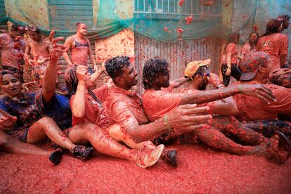 Varias personas se sientan en el suelo cubiertos de pulpa de tomate, durante la Tomatina de este miércoles.