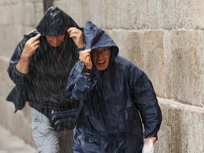 Turistas y peregrinos corren para resguardarse de la lluvia, este martes en la plaza del Obraodiro de Santiago de Compostela.