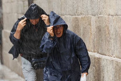 Turistas y peregrinos corren para resguardarse de la lluvia, este martes en la plaza del Obraodiro de Santiago de Compostela.