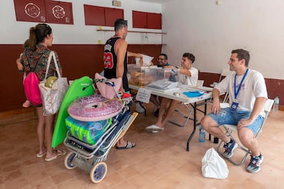 Las veraniegas elecciones de este 23 de julio han convocado a un total de 37,5 millones de electores. En la foto, un hombre deposita su voto en la urna acompañado por su familia tras darse un baño en la playa de Bolnuevo, Mazarrón.