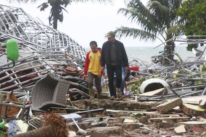 Dois homens caminham entre os escombros em Pandeglang (Indonésia). Local foi devastado por um tsunami.