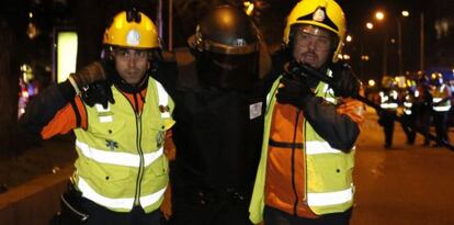 Miembros del SAMUR trasladan a un policía herido durante los altercados.
