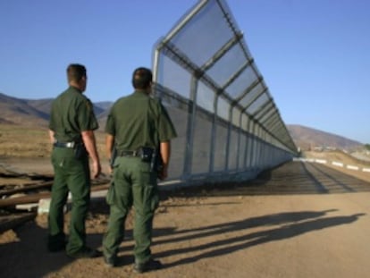 Dos policías vigilan la frontera de México con EE UU.