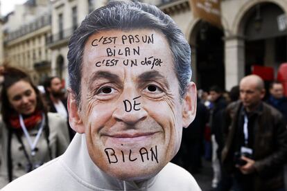 Un hombre porta una careta de Sarkozy durante la manifestación del Primero de Mayo en París, en la que se puede leer: "No es un balance, es una liquidación voluntaria".