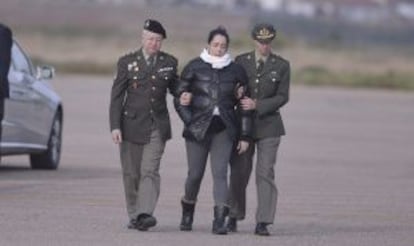 The dead peacekeeper's wife, who is pregnant, is helped towards the coffin at Córdoba airport.