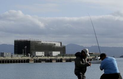 Dos hombres pescan frente a la misteriosa barcaza construida en la bah&iacute;a de San Francisco.