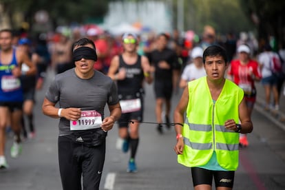 Un corredor de la categoría para personas con discapacidades motriz y visual acompañado de un guía durante la edición XXXIX del el Maratón de la Ciudad de México 2022. 