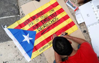 Un joven escribe en una bandera estelada "Por un país con derechos".