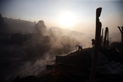 Unos vecinos apagan los rescoldos del incendio.